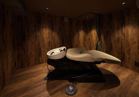 Moderner Backwash in einem stilvollen, holzverkleideten Salonraum, bereit für Haarpflege oder Massage.