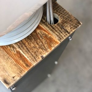 Holztisch mit Metallkabeln und Loch; industrielles Design, Nahaufnahme mit strukturiertem Holz und sichtbaren Kabeln.