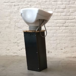 Modernes Haarsalon-Waschbecken auf Metallständer vor Backsteinwand im Industrie-Design.
