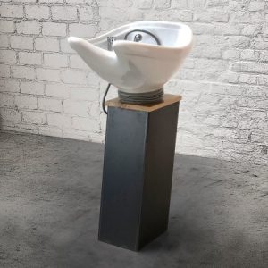 Modernes Haarsalon-Waschbecken auf Metallständer vor Backsteinwand im Industrie-Design.