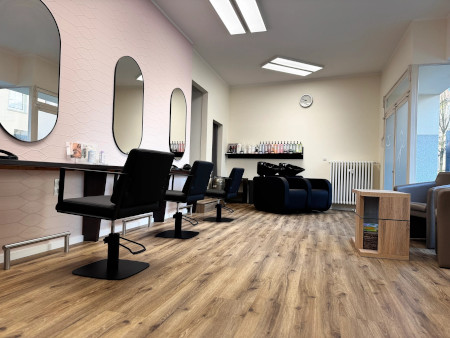 Moderner Friseursalon mit stylischen Spiegeln, schwarzen Stühlen und Holzboden für ein angenehmes Haarstyling-Erlebnis.